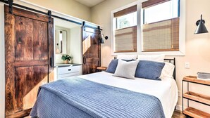 A bedroom with a large bed, wooden sliding doors, and a window with blinds. - 3 Cabins on Lake Conroe: Fish, Swim & Explore! (Willis)