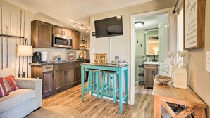 A compact kitchen with wooden cabinets, a microwave, and a teal bar stool. - 3 Cabins on Lake Conroe: Fish, Swim & Explore! (Willis)
