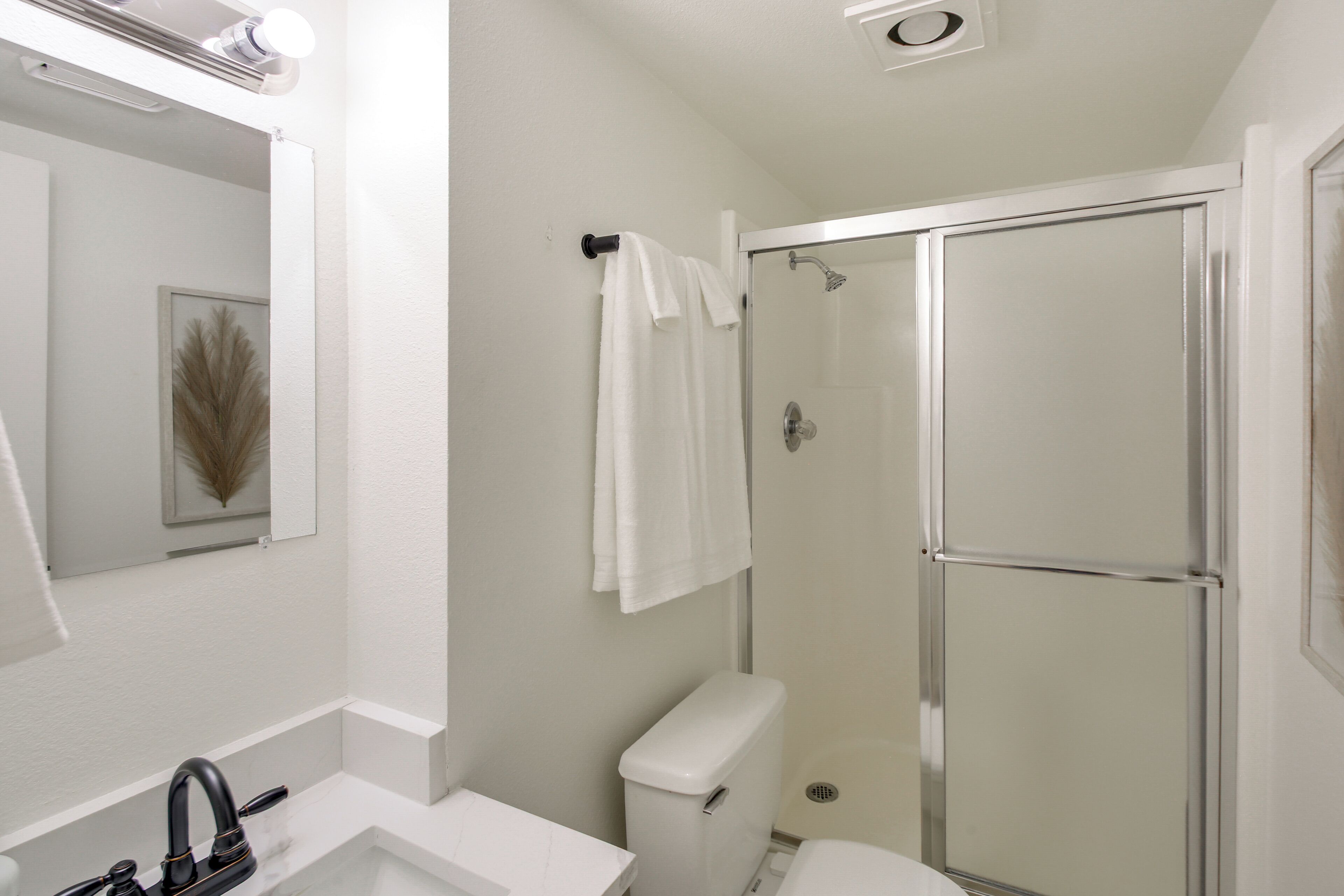 A bathroom with a white sink, a toilet, a shower with a glass door, and a towel hanging on a rack.