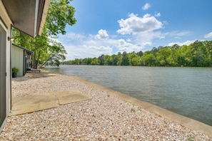 Una propiedad frente al lago con un patio, una terraza de concreto y vistas al lago y al bosque.