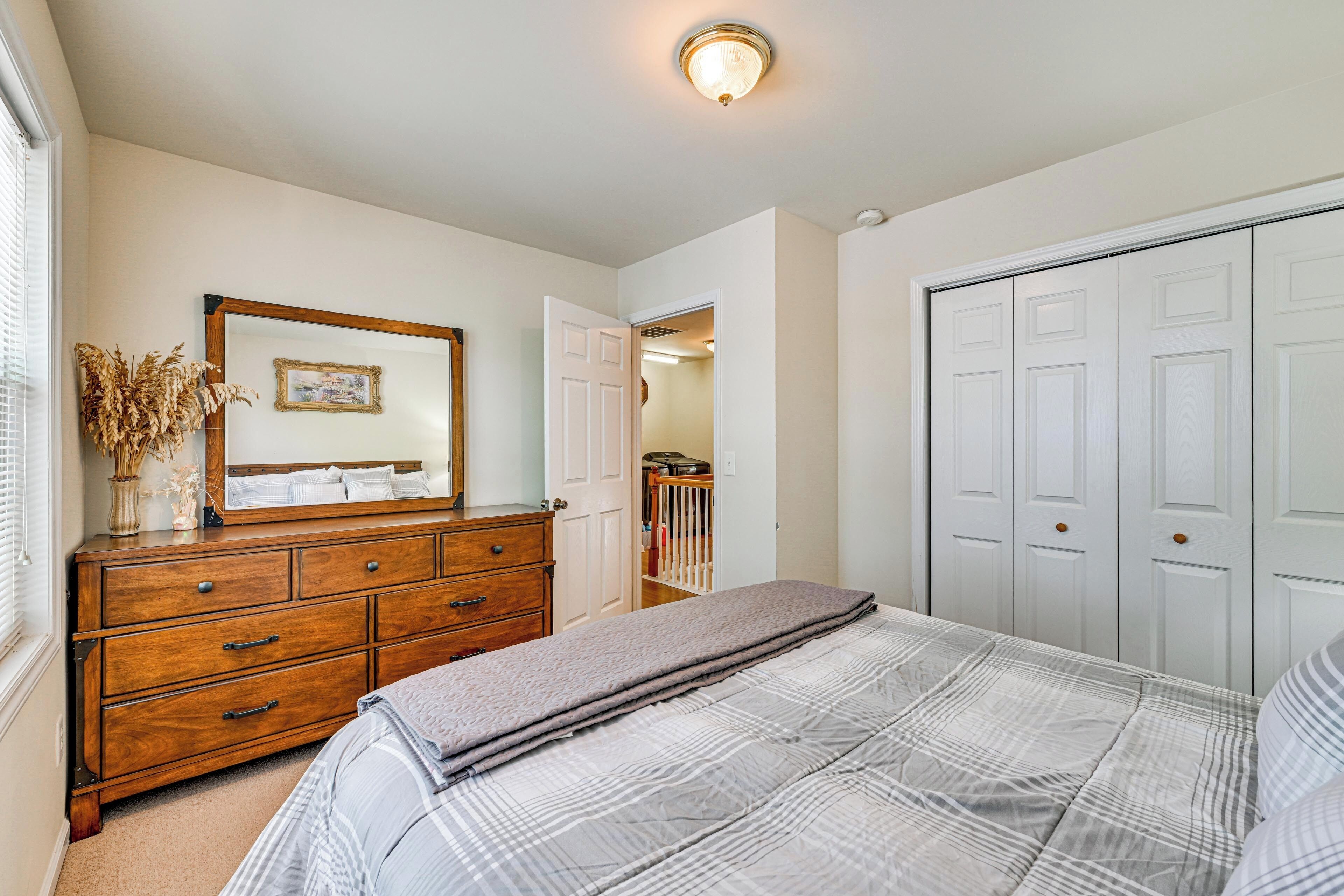 A bedroom with a bed, dresser, wardrobe, and a door leading to a balcony.