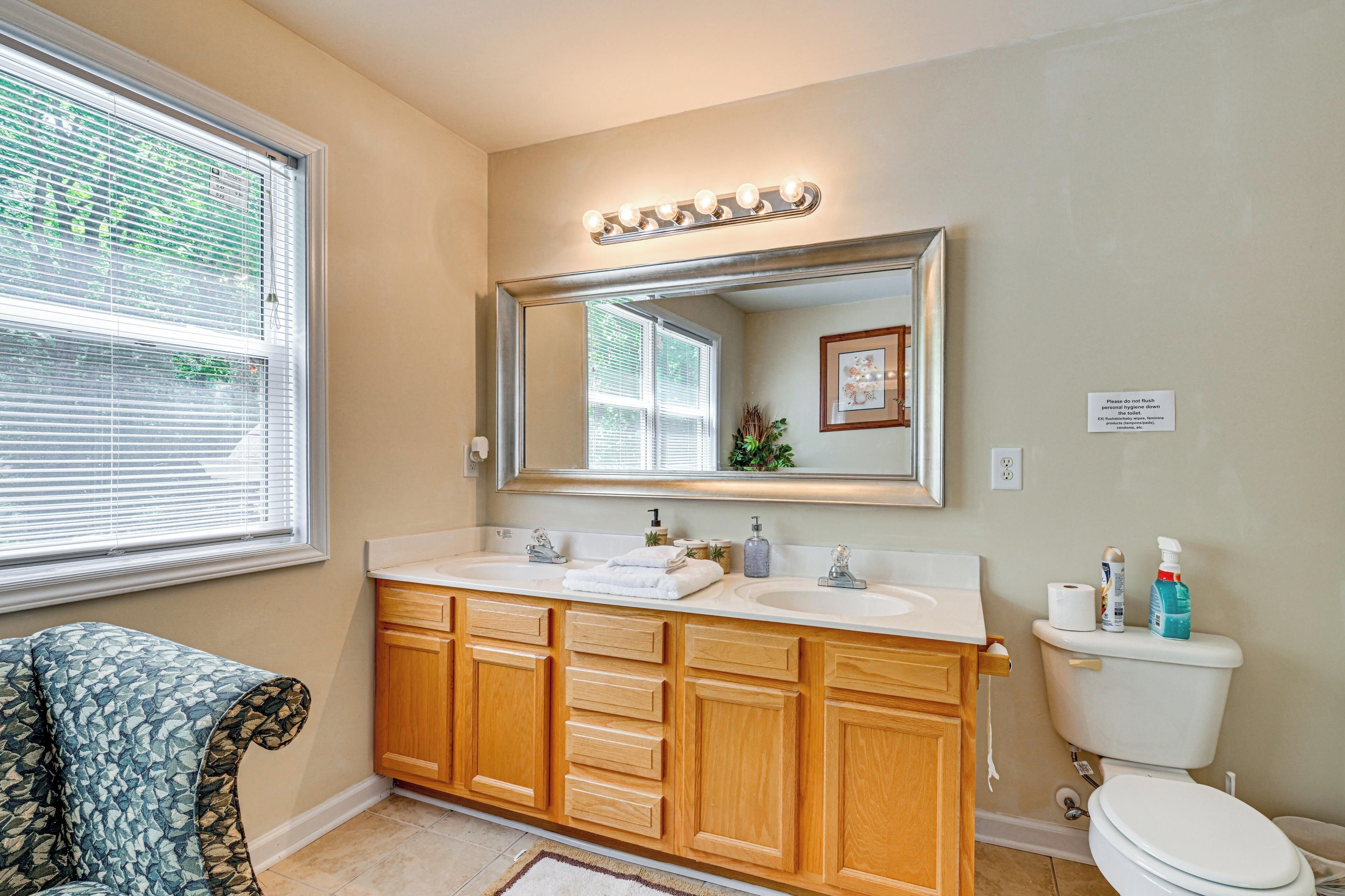 A bathroom with a double vanity, a large mirror, and a toilet.