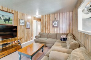 Una sala de estar con un sofá modular, un mueble bajo para la televisión de madera y una mesa de centro.