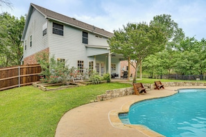 A house with a backyard swimming pool, a wooden deck, and a brick patio.