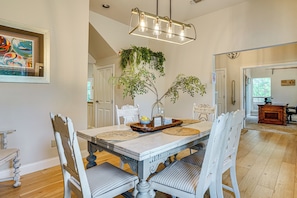 A dining area with a white table, chairs, and a hanging plant.
