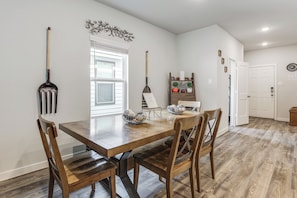 A dining area with a wooden table and chairs, a decorative wall piece, and a window with blinds. - Pool & Dog Park Access! Porter Family Home w/ Yard (Porter)