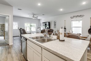 A modern kitchen with a dishwasher, double sink, and a dining area with a table and chairs. - Pool & Dog Park Access! Porter Family Home w/ Yard (Porter)