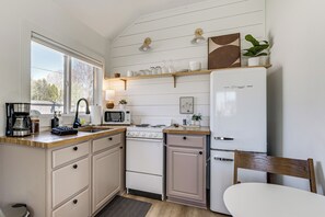 A kitchen with a stove, microwave, and refrigerator, wooden countertops, and a window. - Walkable 3-unit Escape Near Elk Lake & Bay Access! (Elk Rapids)