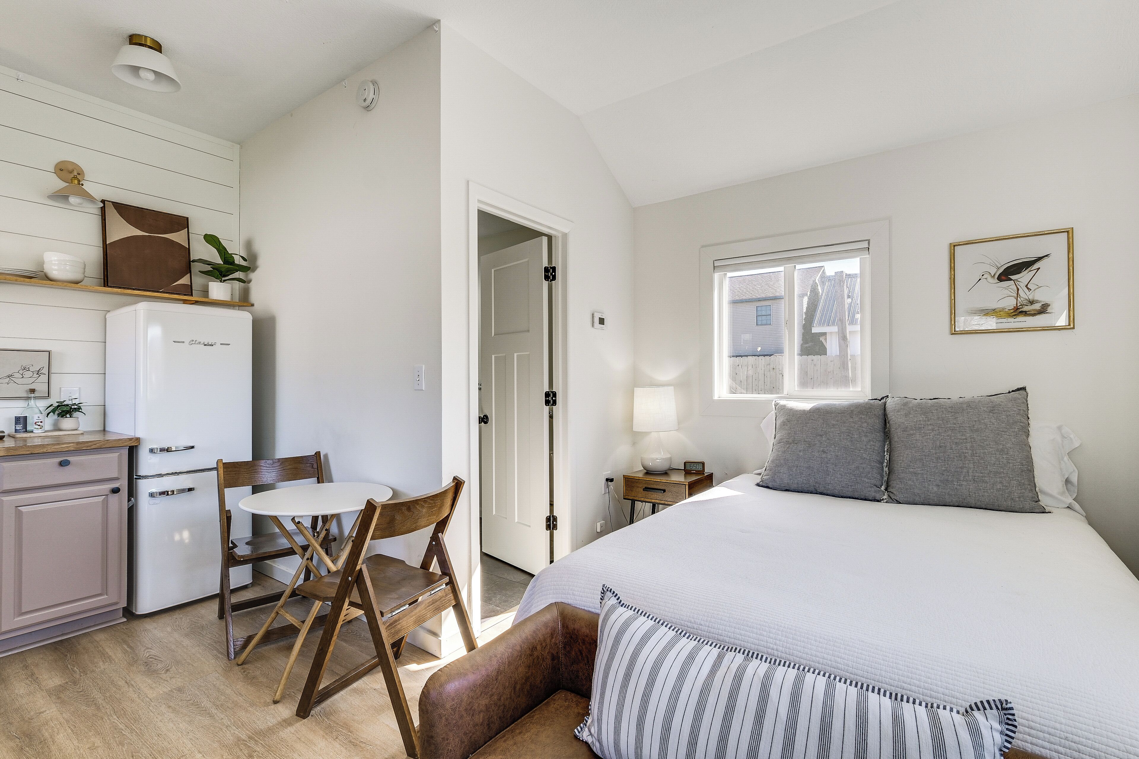 Une chambre à coucher avec un lit, une table de chevet, une lampe et un tableau encadré au mur.