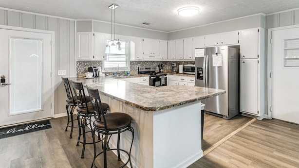 A modern kitchen with white cabinets, a granite countertop, stainless steel appliances, and a bar stool seating area. - 2 Mi to Dtwn Vidalia! Pet-friendly Retreat w/ Yard (Vidalia)