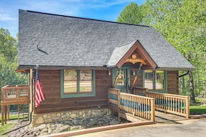 Eine Holzhütte mit Steinfundament, einer Veranda mit Geländer und einer amerikanischen Flagge.