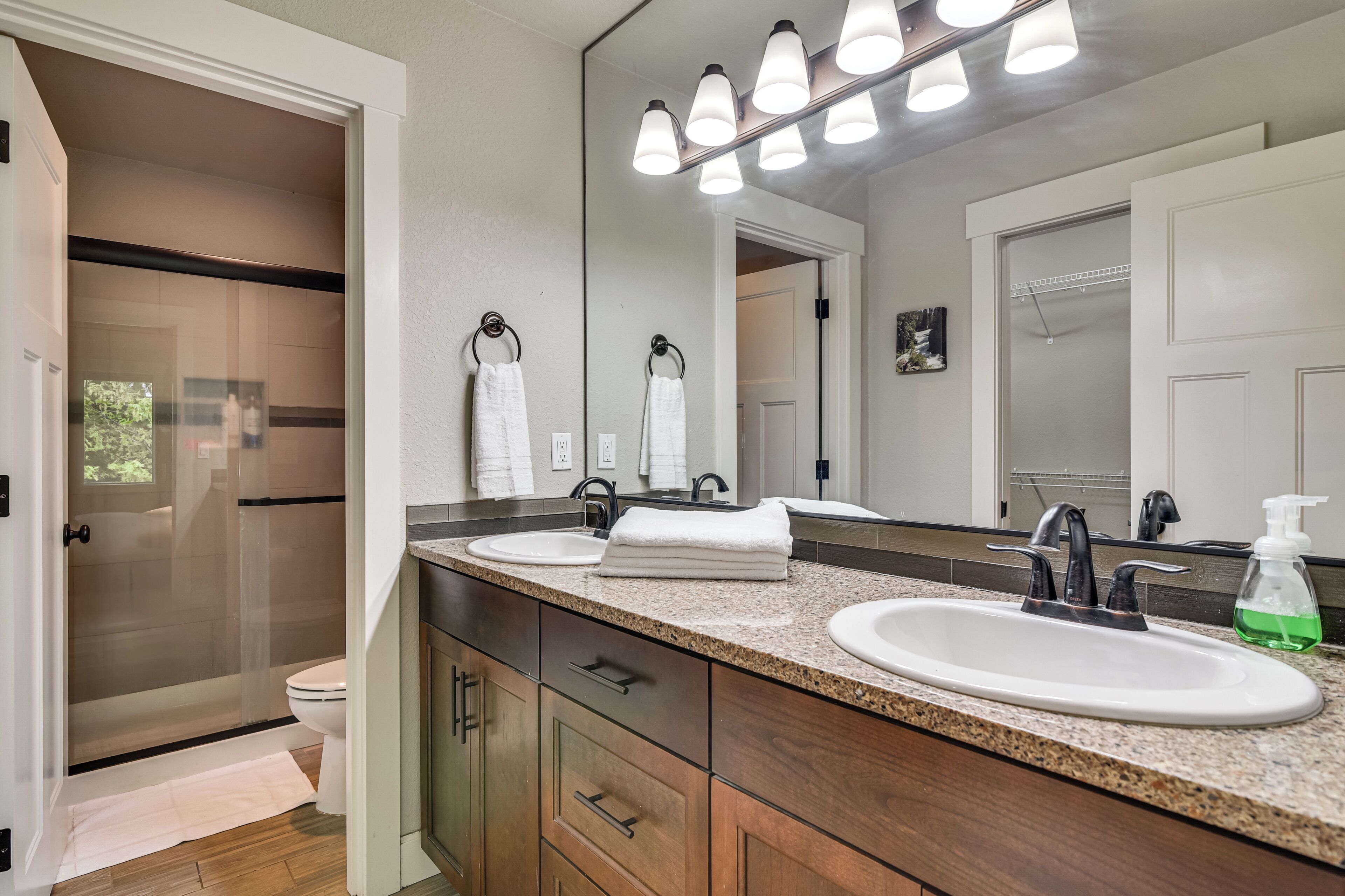 Une salle de bain avec un double lavabo, des meubles en bois, un grand miroir et un espace douche.