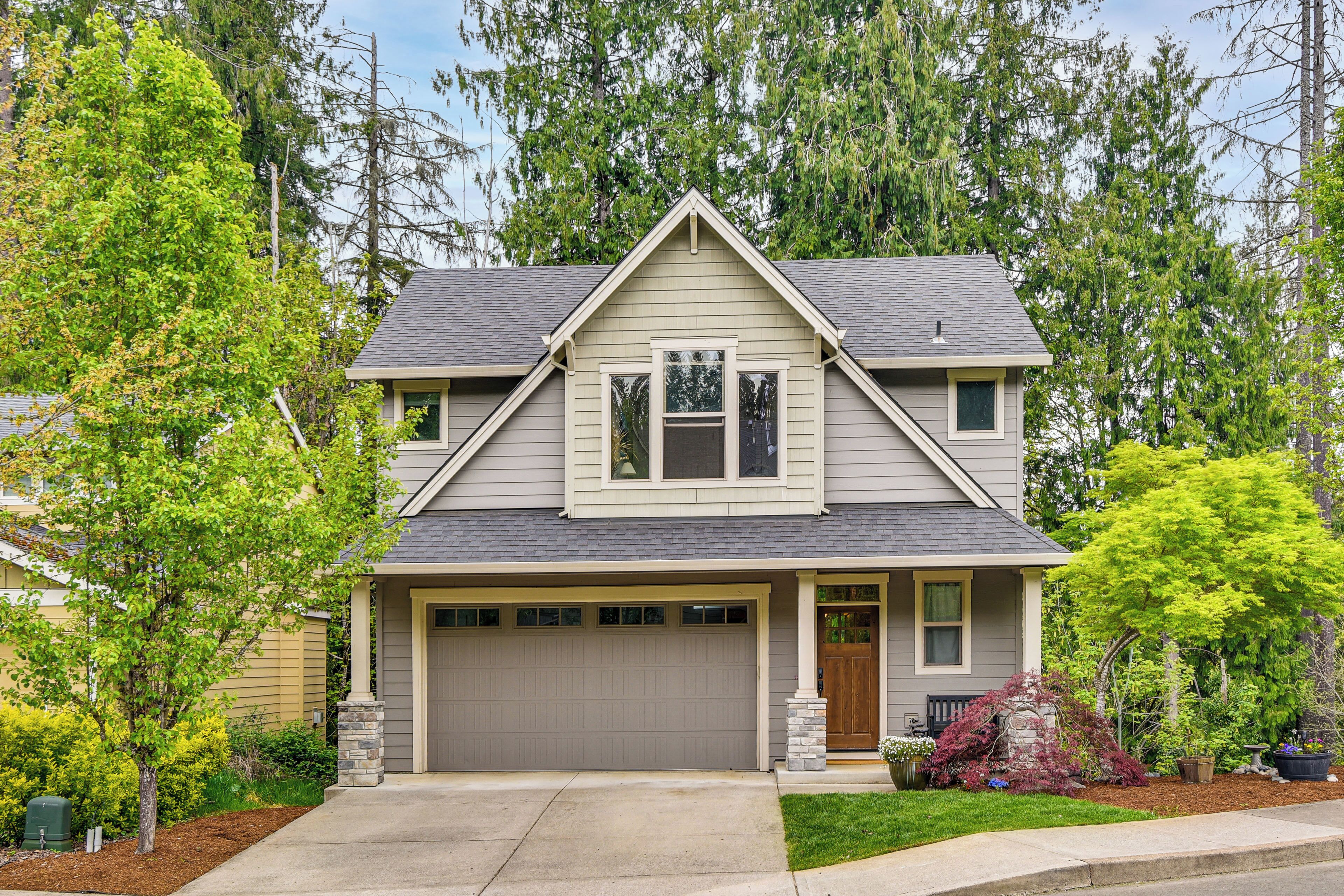 A two-story house with a garage, a front porch, and a well-maintained lawn.