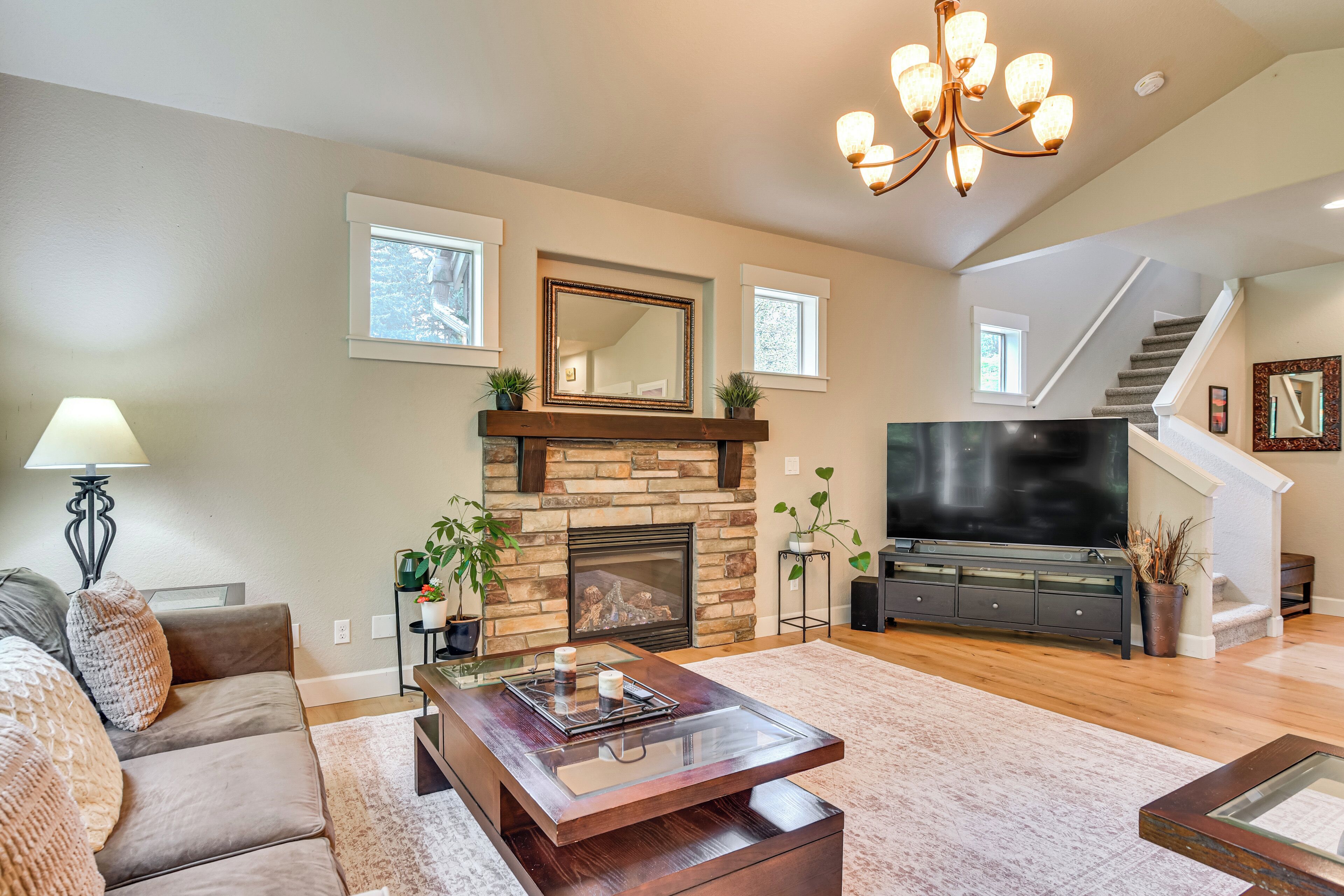 A living room with a fireplace, sofa, coffee table, TV, and staircase.