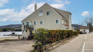 Ein zweigeschossiges Haus mit Steg, Treppe und Hecke.