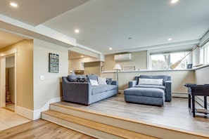 A living room with two grey sofas, a wooden coffee table, and a staircase leading to another level. - Beachfront Bliss on Newfound Lake! Bristol Condo (Bristol)