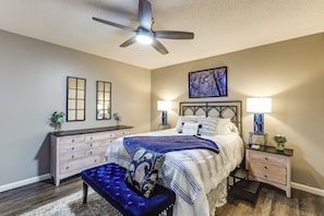 A bedroom with a bed, bedside tables, a ceiling fan, and a large painting on the wall. - Missouri Wine Country Retreat w/ Hot Tub & BBQ (Imperial)