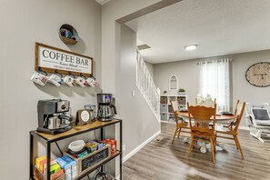 A coffee bar area with a sign, coffee machines, and a shelf with coffee cups and boxes.