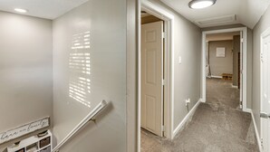 A hallway with a carpeted floor, white walls, and a door leading to another room. - Missouri Wine Country Retreat w/ Hot Tub & BBQ (Imperial)