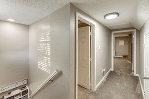 A hallway with a carpeted floor, white walls, and a door leading to another room. - Missouri Wine Country Retreat w/ Hot Tub & BBQ (Imperial)