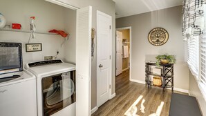 A laundry room with a washing machine, dryer, and a shelf with cleaning supplies. - Missouri Wine Country Retreat w/ Hot Tub & BBQ (Imperial)