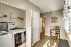 A laundry room with a washing machine, dryer, and a shelf with cleaning supplies. - Missouri Wine Country Retreat w/ Hot Tub & BBQ (Imperial)