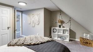 A bedroom with a bed, a white console table, a wall clock, and a door. - Missouri Wine Country Retreat w/ Hot Tub & BBQ (Imperial)