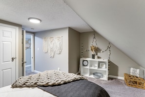 A bedroom with a bed, a white console table, a wall clock, and a door. - Missouri Wine Country Retreat w/ Hot Tub & BBQ (Imperial)