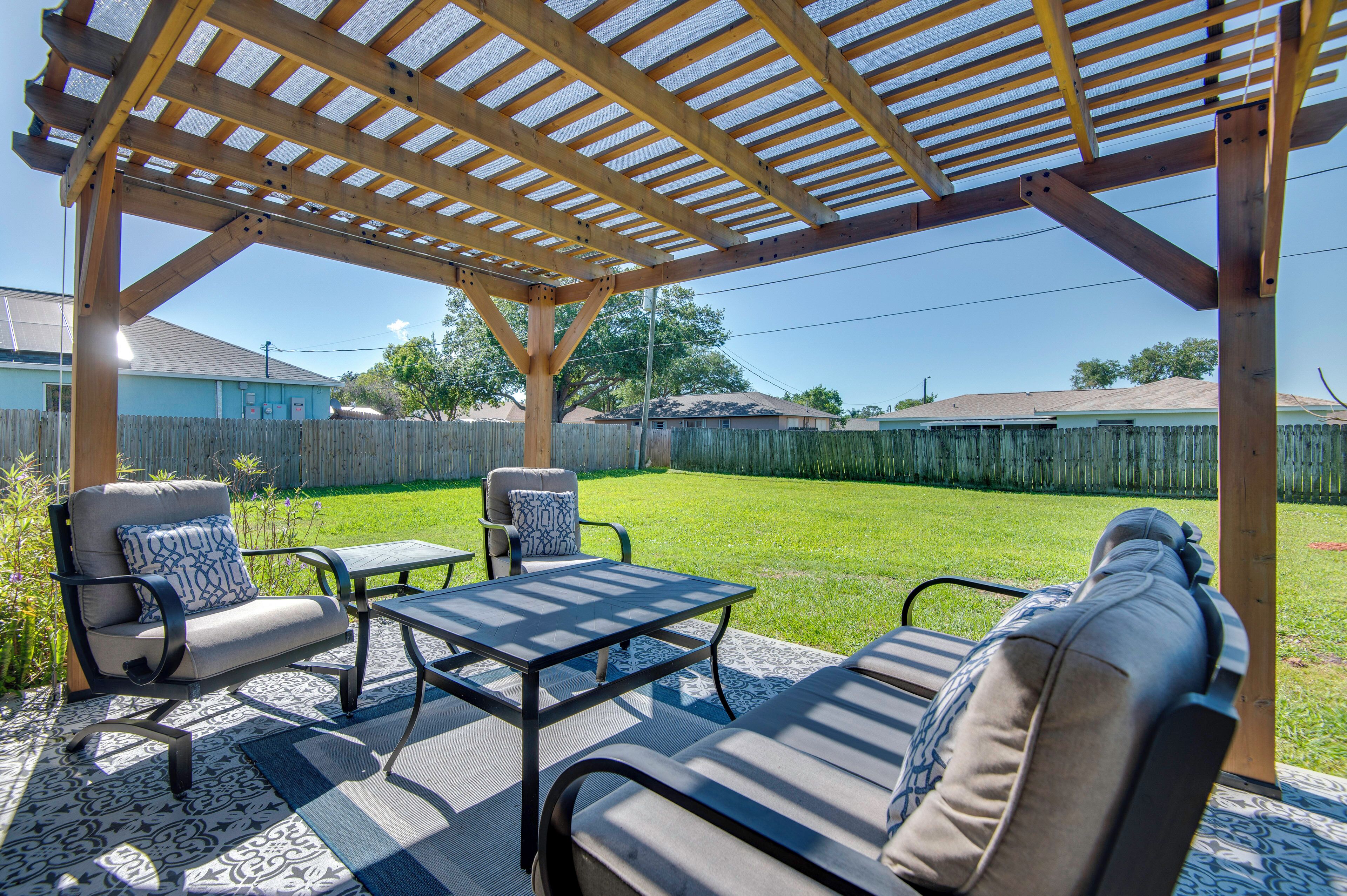 Eine überdachte Terrasse mit Gartenmöbeln und einer Holz-Pergola.