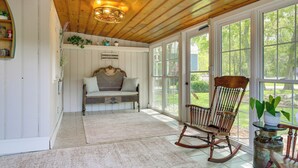 A room with a wooden ceiling, a rocking chair, a bench with cushions, and large windows. - Historic Home w/ Hot Tub and Game Room in Augusta (Augusta)