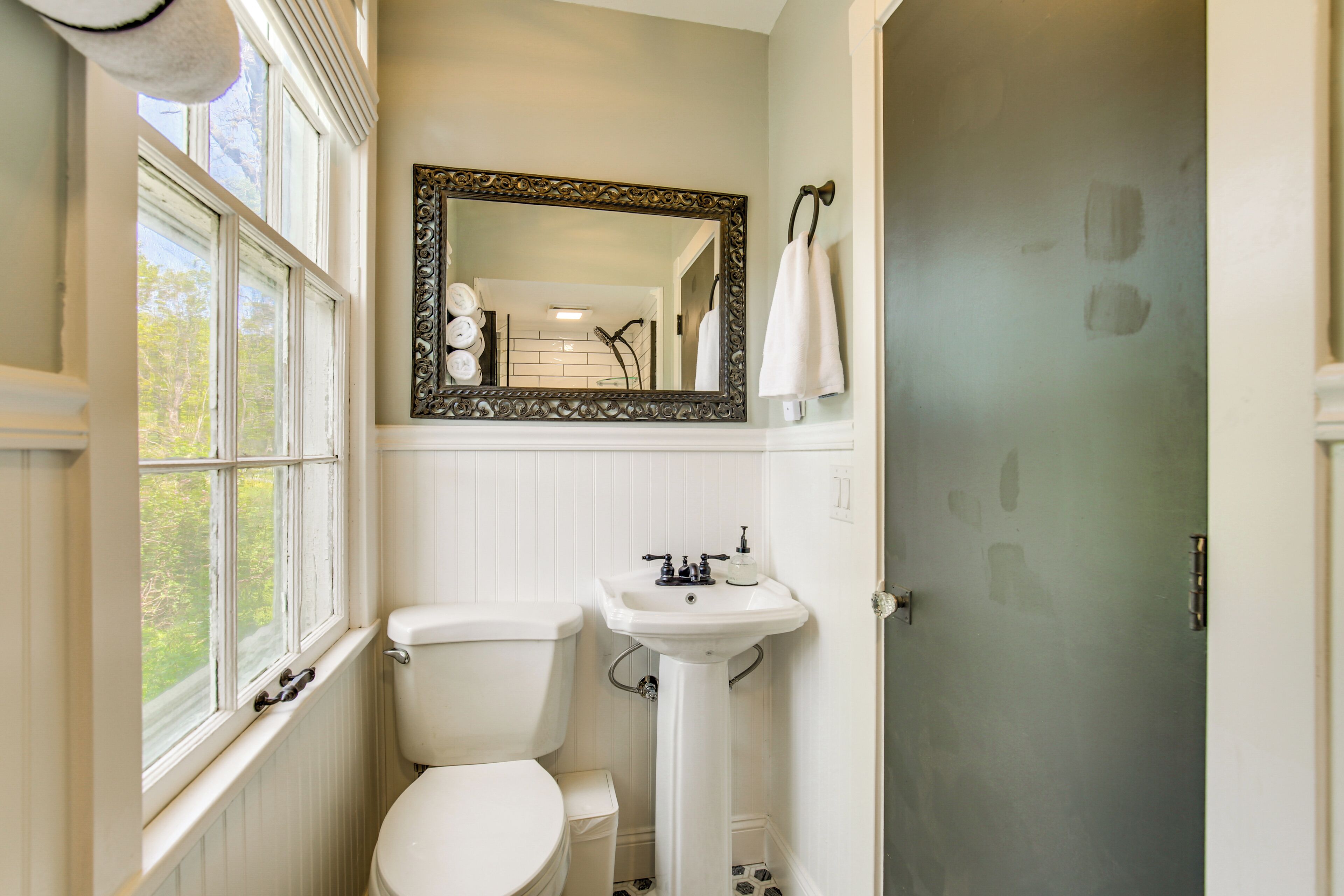 A bathroom with a toilet, sink, and window.