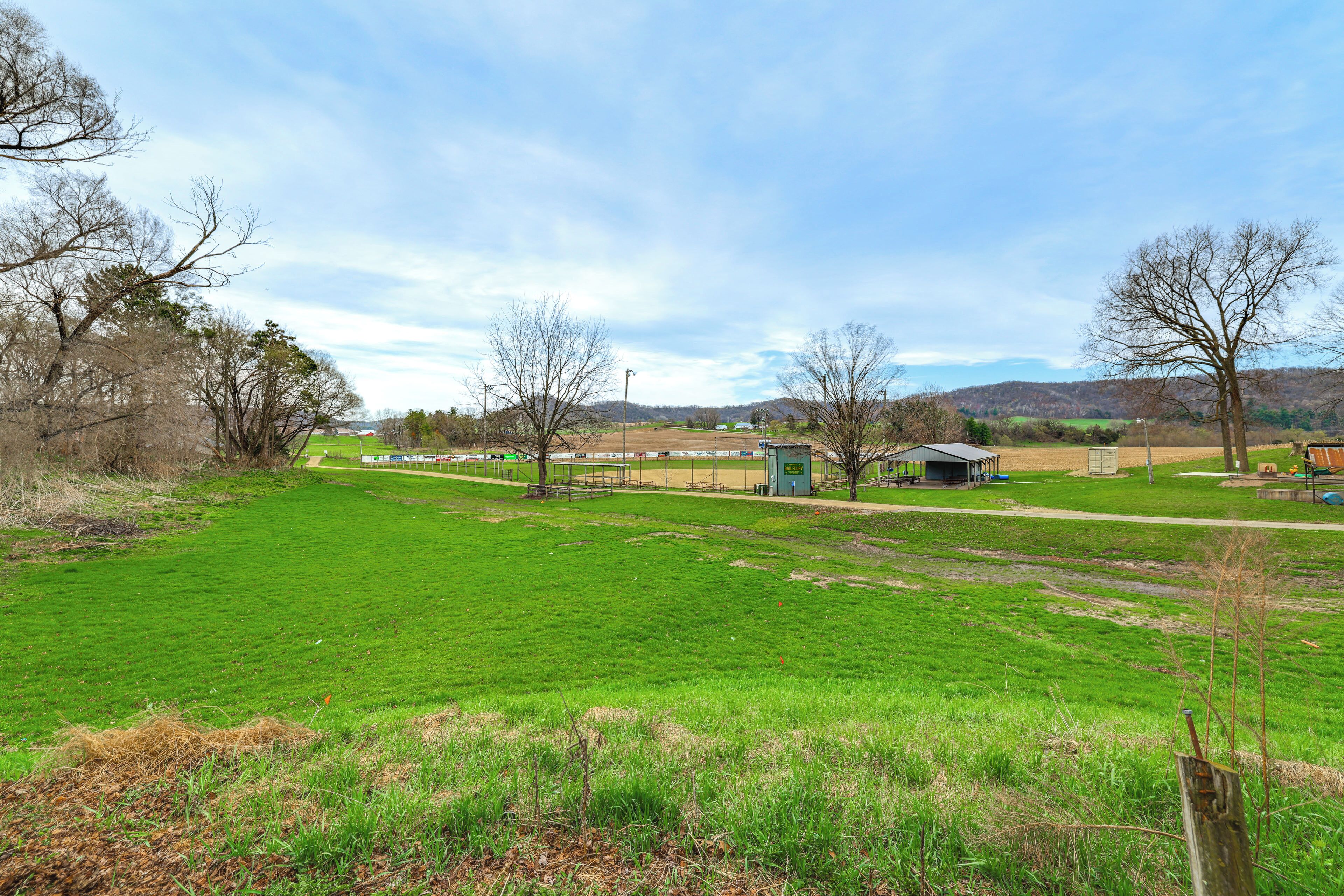 A rural landscape with a green field, a small building, and trees.