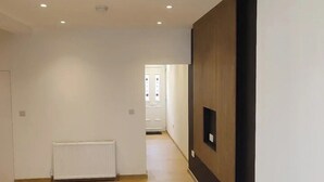 A hallway with a radiator, a wooden floor, and a door at the end. - 4 Bed Exeter City Center (New images coming soon) (Devon)