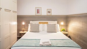 Une chambre d’hôtel comprenant un lit, des tables de chevet, une tête de lit fixée au mur et des œuvres d’art encadrées accrochées au mur.