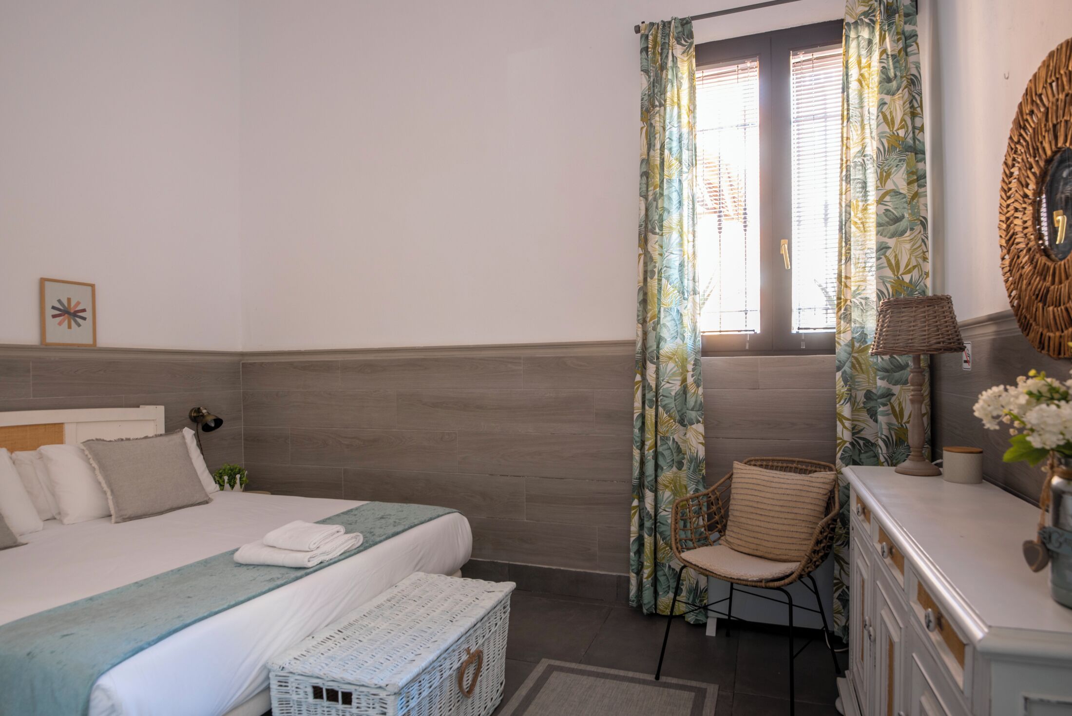 A bedroom with a bed, a chair, a dresser, and a window with curtains.