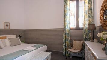 A bedroom with a bed, a chair, a dresser, and a window with curtains.