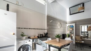Une cuisine moderne équipée d’un lave-linge, d’une table à manger, de chaises et d’une horloge murale.