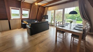 A loft-style room with a dining area, a sofa, and a view of the outdoors. - Storchennest roof-only house: Comfortable vacation home on the North Sea in Butjadingen (Butjadingen)