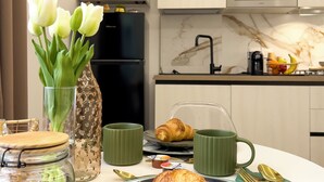 A breakfast setting with a croissant, a jar of cereal, a vase with flowers, and a microwave in a modern kitchen.