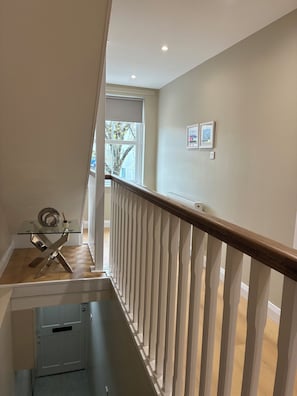 A staircase with a wooden handrail, a glass table with a decorative item, and a door leading to another room.