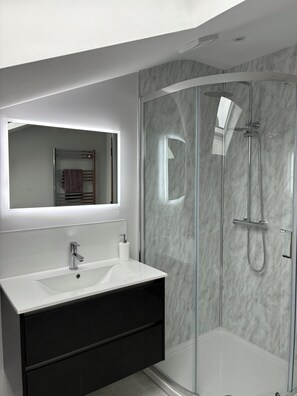 A modern bathroom with a glass-enclosed shower, a white sink, and a dark vanity. - Central location, luxury apartment close to the beach, pubs and restaurants. (Warrenpoint)