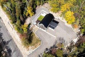 An aerial view of a property with a large building, a driveway, and surrounding trees. - Clematites | Private Spa & Games | Nature & Lake (Matawinie Regional County Municipality)