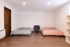A room with two beds, a chair, and a wooden door. - Clematites | Private Spa & Games | Nature & Lake (Matawinie Regional County Municipality)