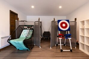 A room with a bed, a target on a stand, and a wardrobe. - Clematites | Private Spa & Games | Nature & Lake (Matawinie Regional County Municipality)