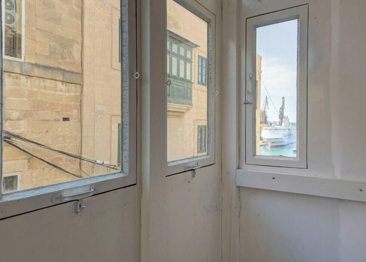 Una stanza con tre finestre, ognuna con vista su edifici e una gru.
