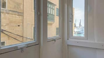 Una stanza con tre finestre, ognuna con vista su edifici e una gru.