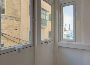 Ein Zimmer mit drei Fenstern, jedes mit Blick auf Gebäude und einen Kran.