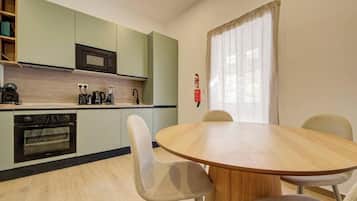 Une cuisine compacte équipée d’un four à micro-ondes, d’un four traditionnel et d’une table à manger avec des chaises.