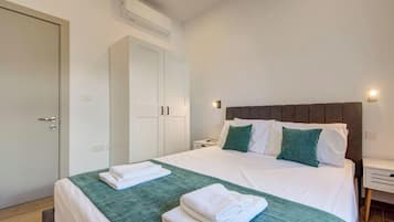 Une chambre d’hôtel équipée d’un lit, d’une armoire, d’une table de chevet et d’un climatiseur fixé au mur.