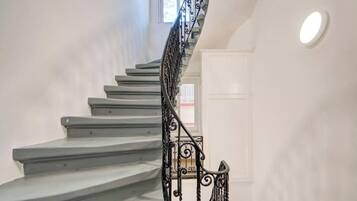 Un escalier avec une rampe en métal noir et un mur blanc.